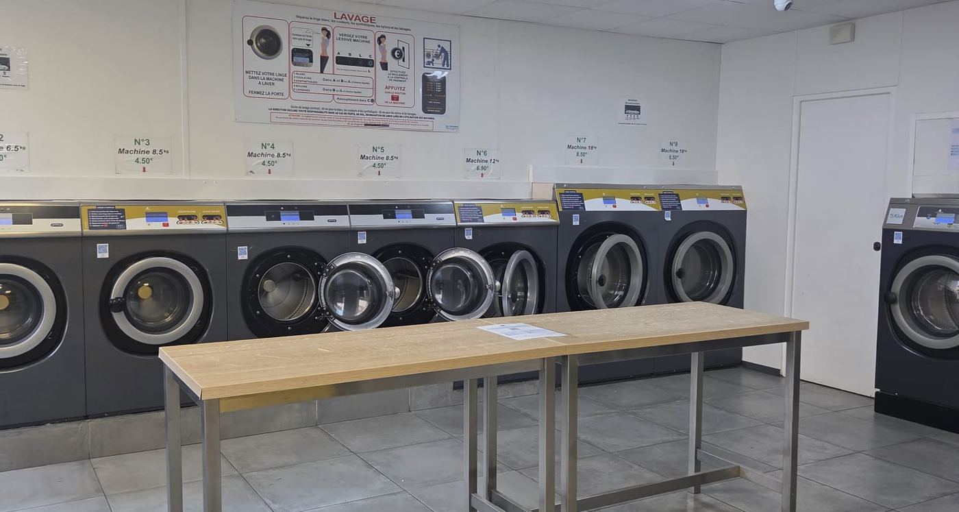 La rangée de laveuses, avec leur numéro, leur capacité et leur prix affichés au-dessus