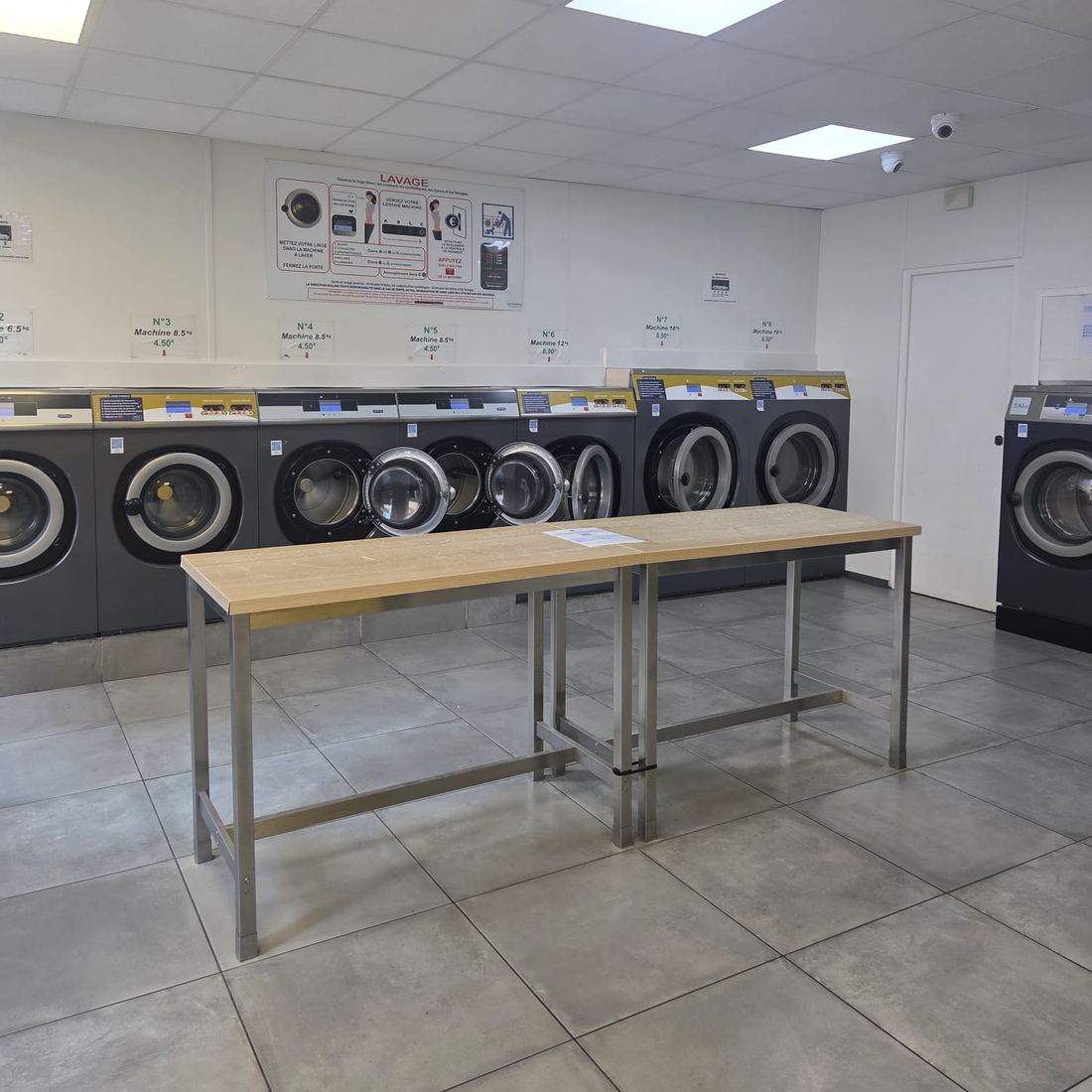 La salle de City Laverie : la rangée de laveuses et la table de pliage