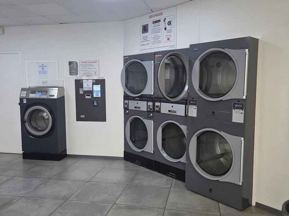 Les séchoirs superposés, la laveuse de 15 kg et la centrale de paiement